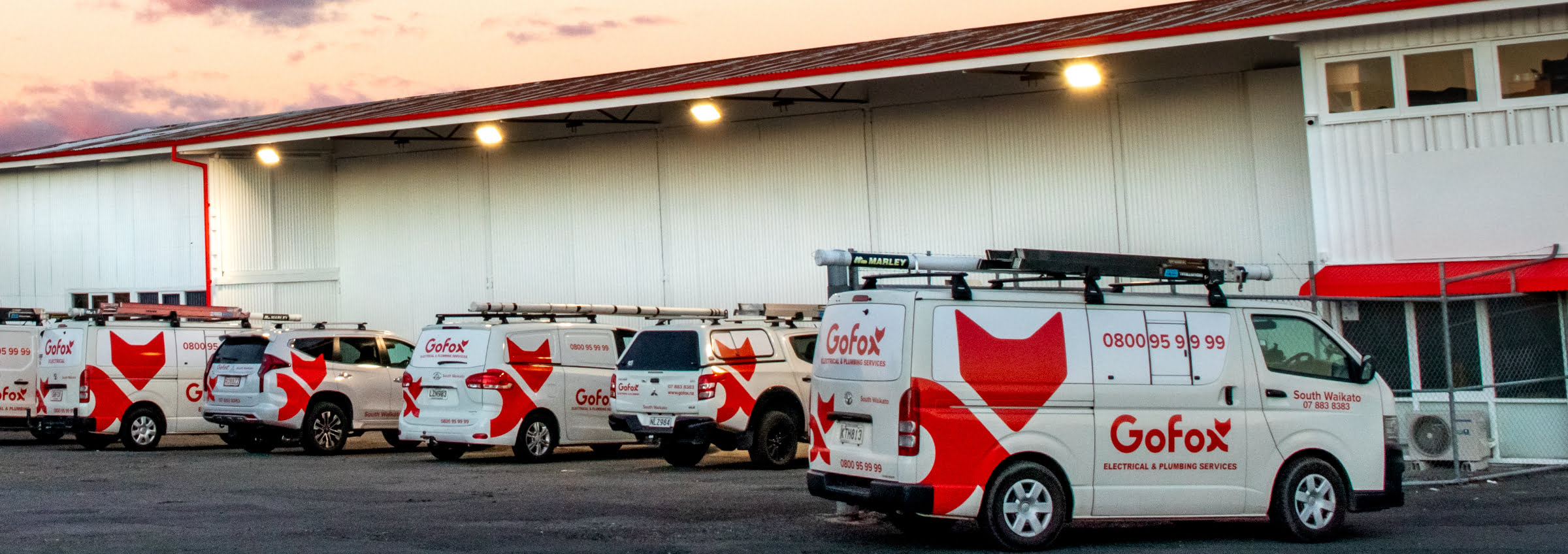 Electrical and Plumbing Franchise fleet showing multiple GoFox branded service vehicles lined up outside a depot, representing franchise operations.