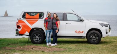 GoFox Franchise Opportunities showcased with a GoFox-branded ute parked by the beach as two team members stand smiling beside the vehicle.