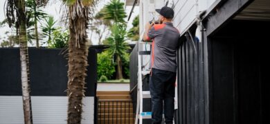 Outdoor Electrical Upgrades being completed by a GoFox electrician installing equipment on a home exterior while standing on a ladder