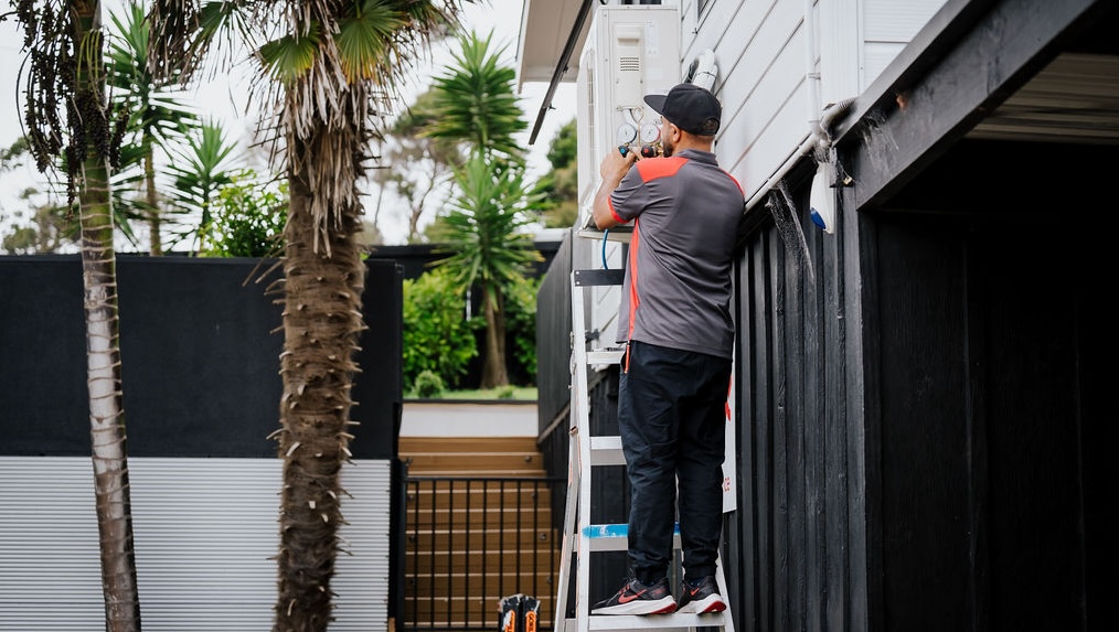 Outdoor Electrical Upgrades being completed by a GoFox electrician installing equipment on a home exterior while standing on a ladder