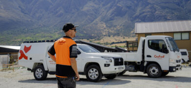 Trades Businesses Hit a Growth Ceiling showing a GoFox worker standing beside branded service vehicles at a regional worksite with mountains in the background