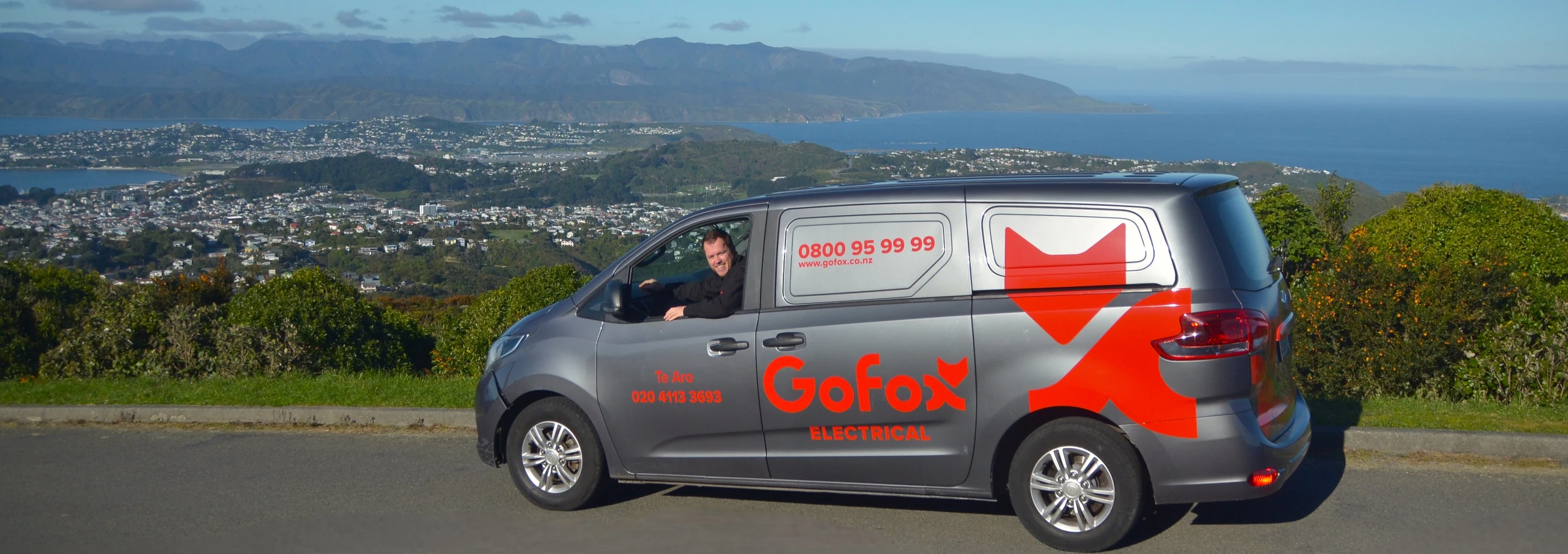 Local Electrician Wellington GoFox Electrical Te Aro van parked at scenic lookout overlooking Wellington city and harbour with technician inside vehicle