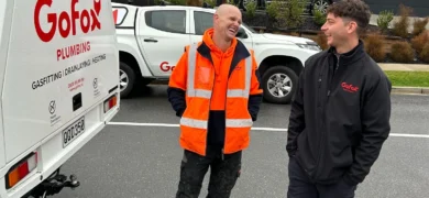 Electrical and Plumbing Franchising NZ showing GoFox Electrical and GoFox Plumbing franchise owners chatting beside branded service vehicles on site