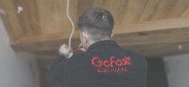 When to call an electrician for home electrical issues, showing a GoFox Electrical technician working on wiring inside a house.
