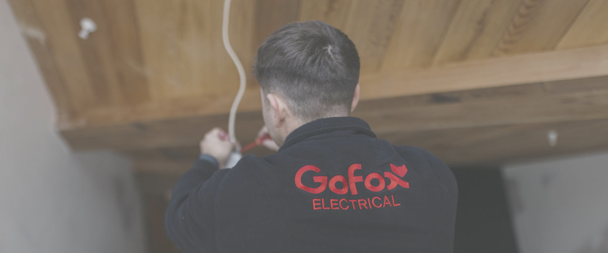 When to call an electrician for home electrical issues, showing a GoFox Electrical technician working on wiring inside a house.
