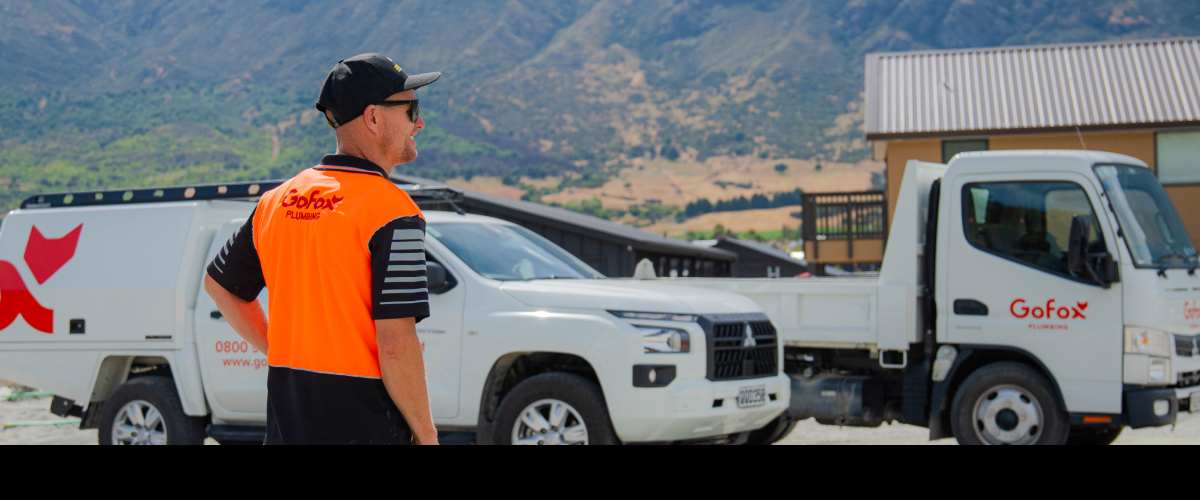Is joining an electrical or plumbing franchise the right move – GoFox plumbing team member on site with branded vehicles in the background
