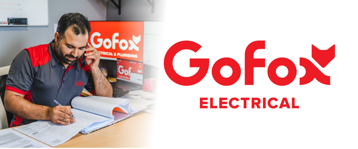 Find a reliable electrician: GoFox Electrical tradesperson reviewing job documentation at a desk while on a call, with the GoFox Electrical and Plumbing logo on screen behind him, alongside the GoFox Electrical brand logo.