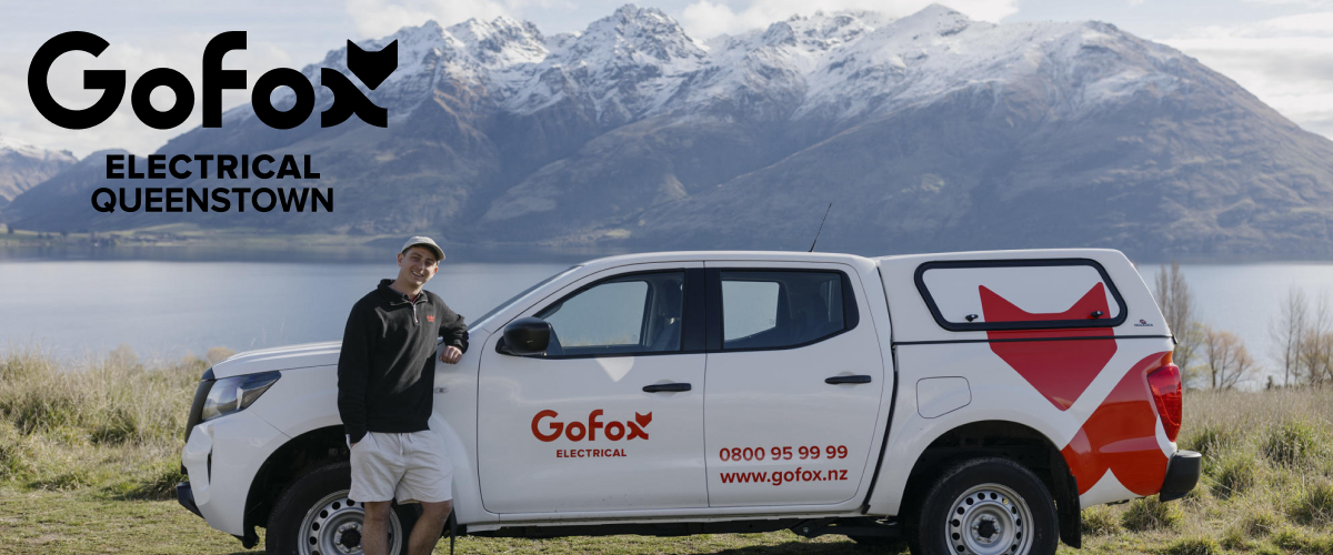 Electrician Queenstown solar and new build specialist from GoFox Electrical Queenstown standing beside branded service vehicle with Queenstown mountains in the background
