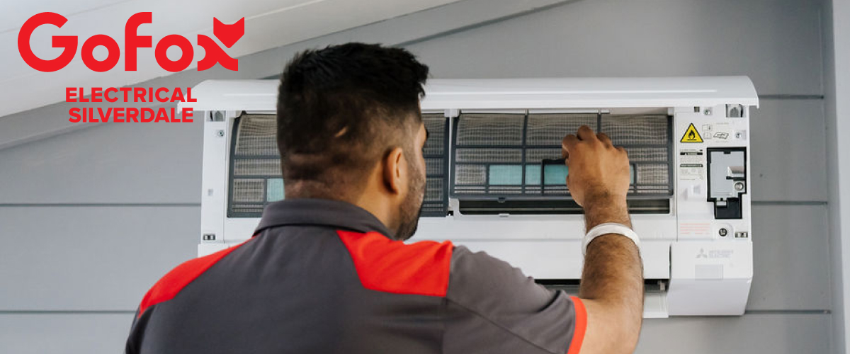 Air Conditioning Service Silverdale by GoFox Electrical technician servicing a wall-mounted heat pump system in a residential property.