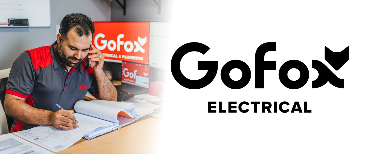 Solar installer: a GoFox electrician reviewing paperwork and taking a call at the office, with GoFox Electrical and Plumbing branding.