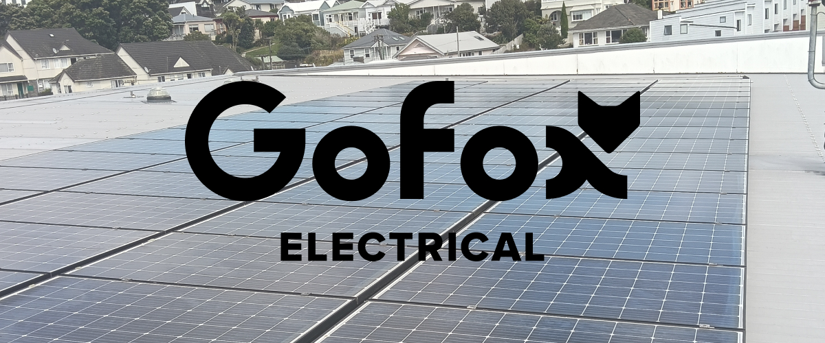 What size solar system: rows of solar panels installed on a flat New Zealand roof, with hillside homes in the background and the GoFox Electrical logo.