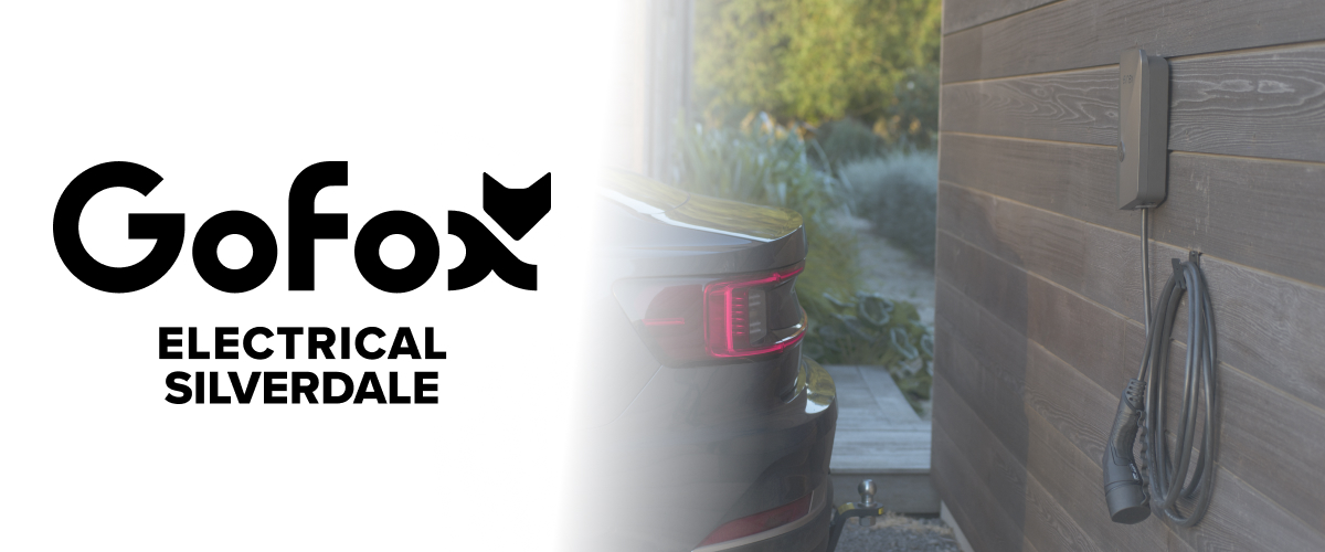 EV charger installation Silverdale: wall-mounted home EV charger with charging cable, parked car beside it, GoFox Electrical Silverdale branding.